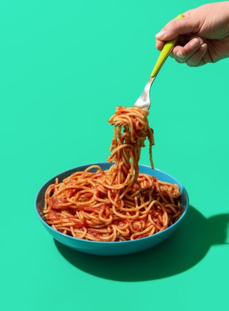 Spaghetti Pomodoro on a fork, minimalist on a green background