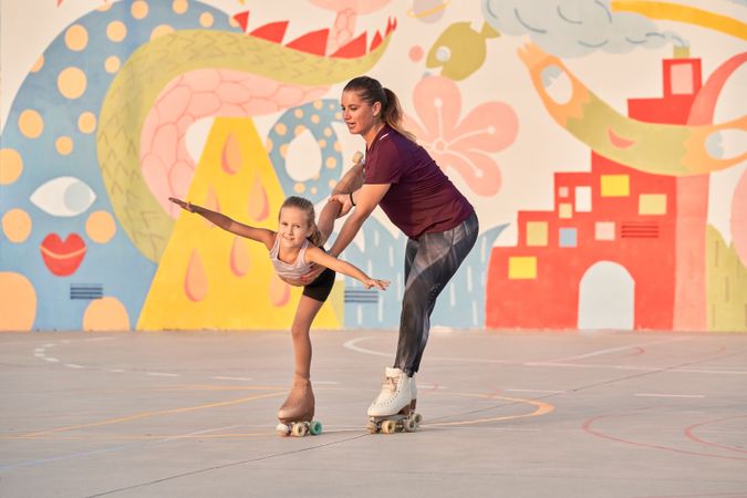 Little sport girl with trainer practicing roller skating