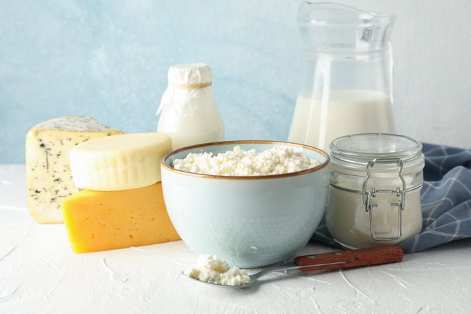 Different dairy products on neutral table against blue background