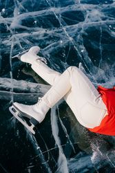 Happy woman in skates lying on ice