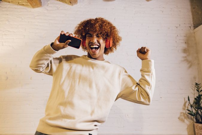 Young man listening music dancing on a sofa.