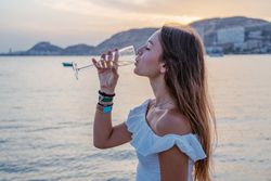Young woman enjoying wine near sea