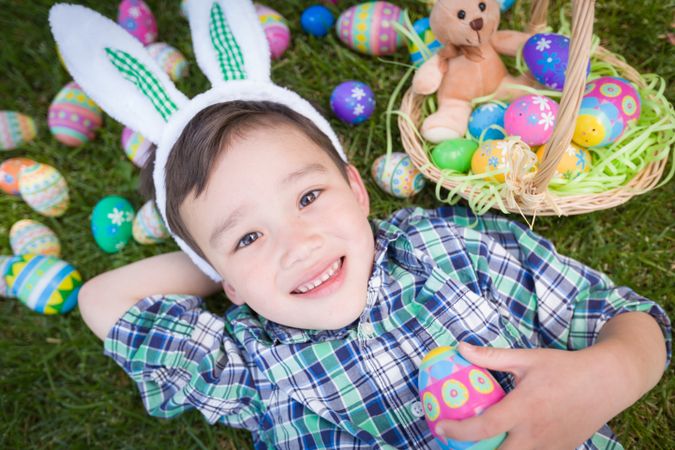 Boy Outside Wearing Rabbit Ears Playing with Easter Eggs