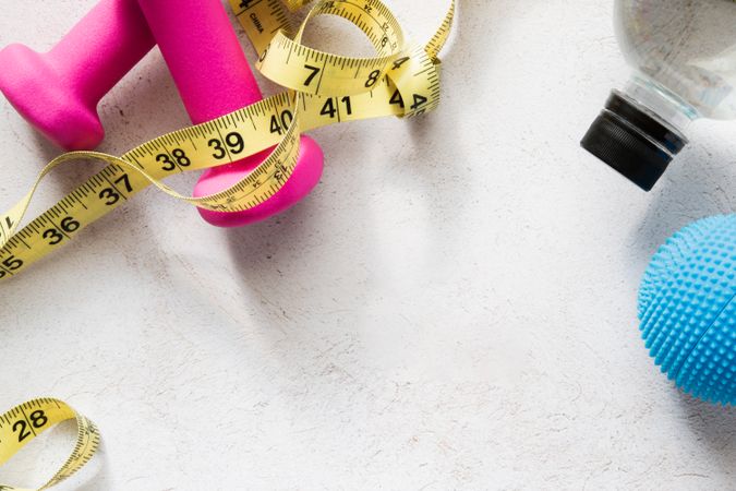 Dumbbells, Massage Ball, Water Bottle And Measuring Tape on Fitness-Inspired Background