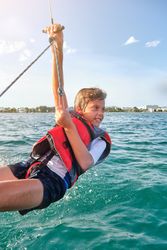 Smiling cute kid balancing on rope over sea during cruise