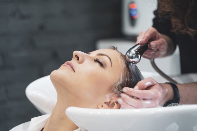 Stylist washing hairs to young woman