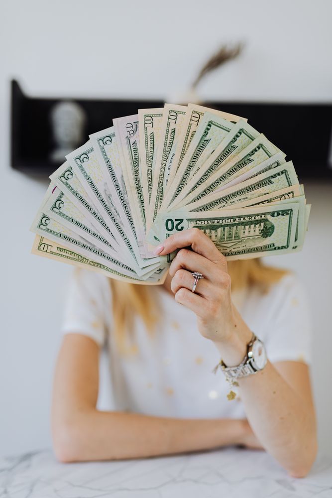 Woman holding fan of US dollar bill paper money