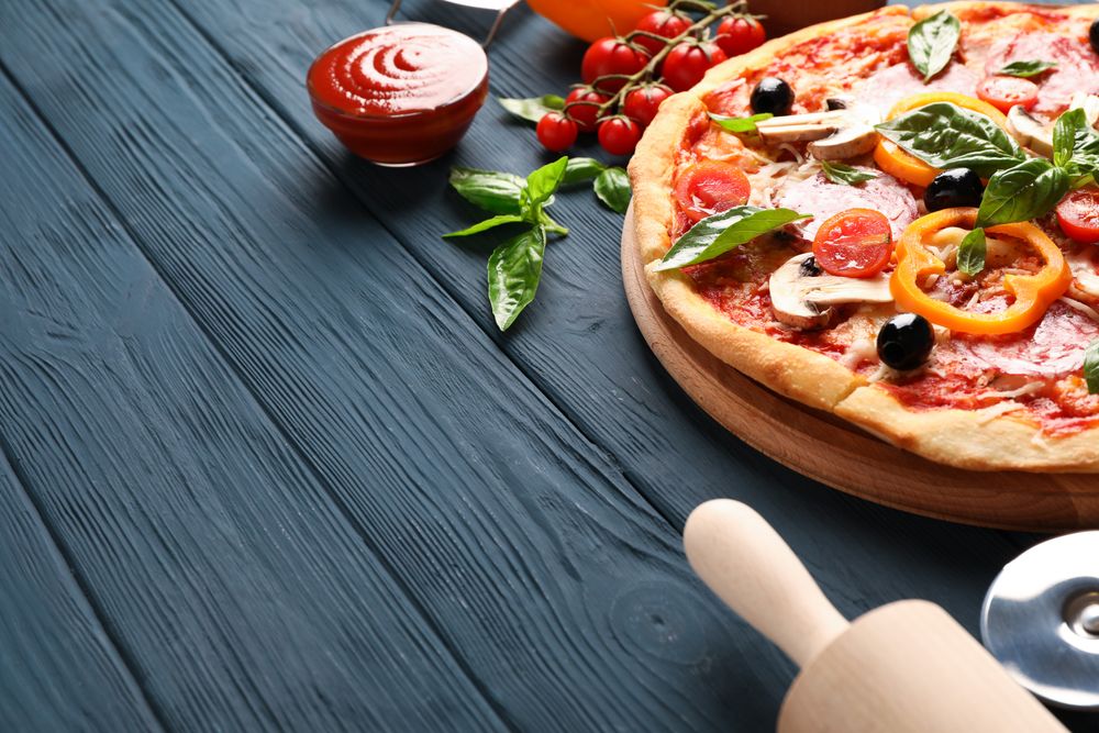 Delicious pizza and ingredients on wooden background, copy space