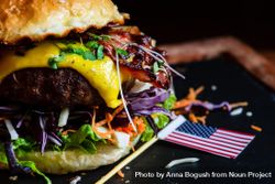 Close up of bacon burger with melted cheese and vegetables with mini flag 5Q2mxg