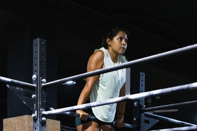 Hispanic sportswoman exercising on crossbar