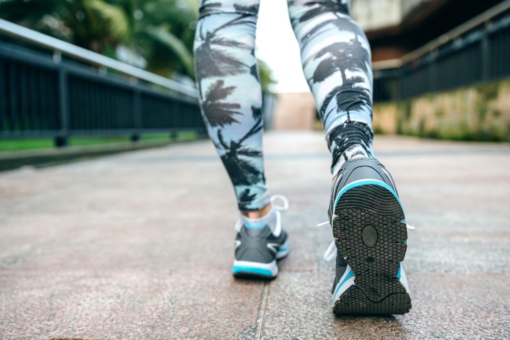 Legs of woman ready to run wearing sneakers and tropical leggings