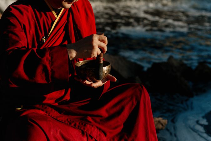 Cropped image of Buddhist monk holding a Tibetan singing bowl