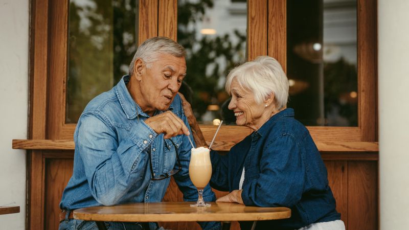 Beautiful portrait of a man and woman sitting at cafe table talking with cold coffee on table