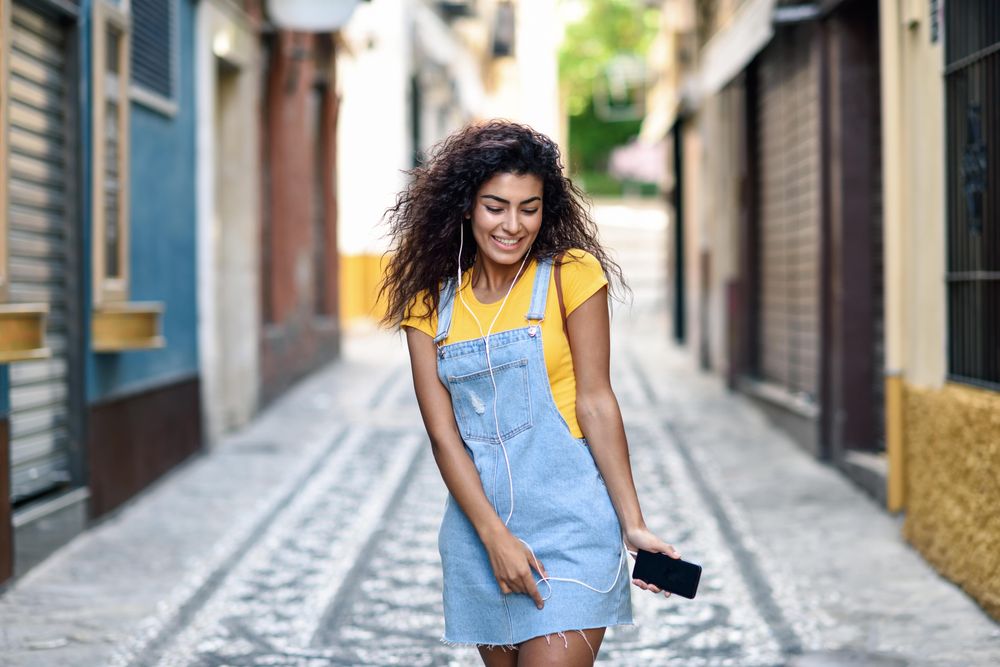 Arab woman listening to music with earphones outdoors