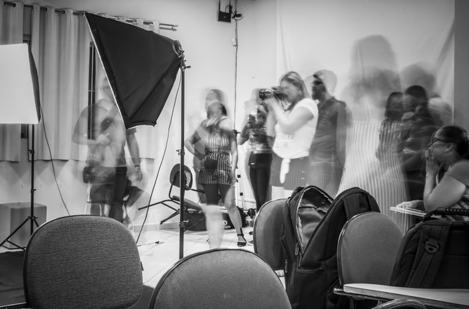 Grayscale photo of a photographer shooting in a room filled with people