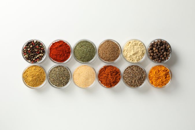 Two rows of colorful spices on plain background