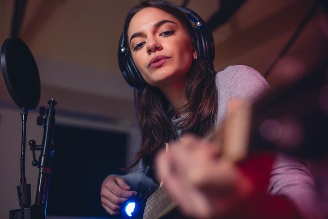 Woman guitarist playing guitar in a recording studio