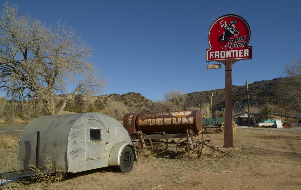 An old camper stands beneath a Frontier Gasoline station sign at the Classical Gas Museum