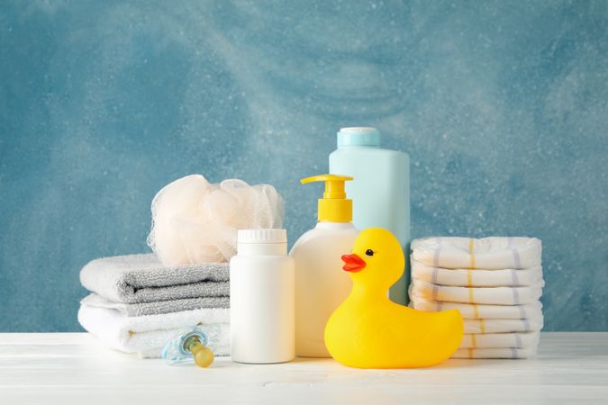 Baby hygiene accessories on wooden table against blue background