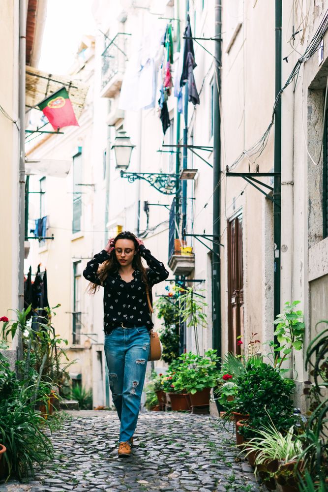 Young casual brunette walking on cobblestone street of old city