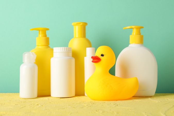 Baby hygiene accessories on yellow table against mint background