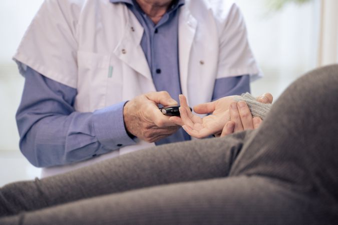 Doctor performing a blood sugar test on a patient's finger.