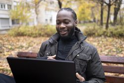 Male Talking During Virtual Meeting on Bench Outside.