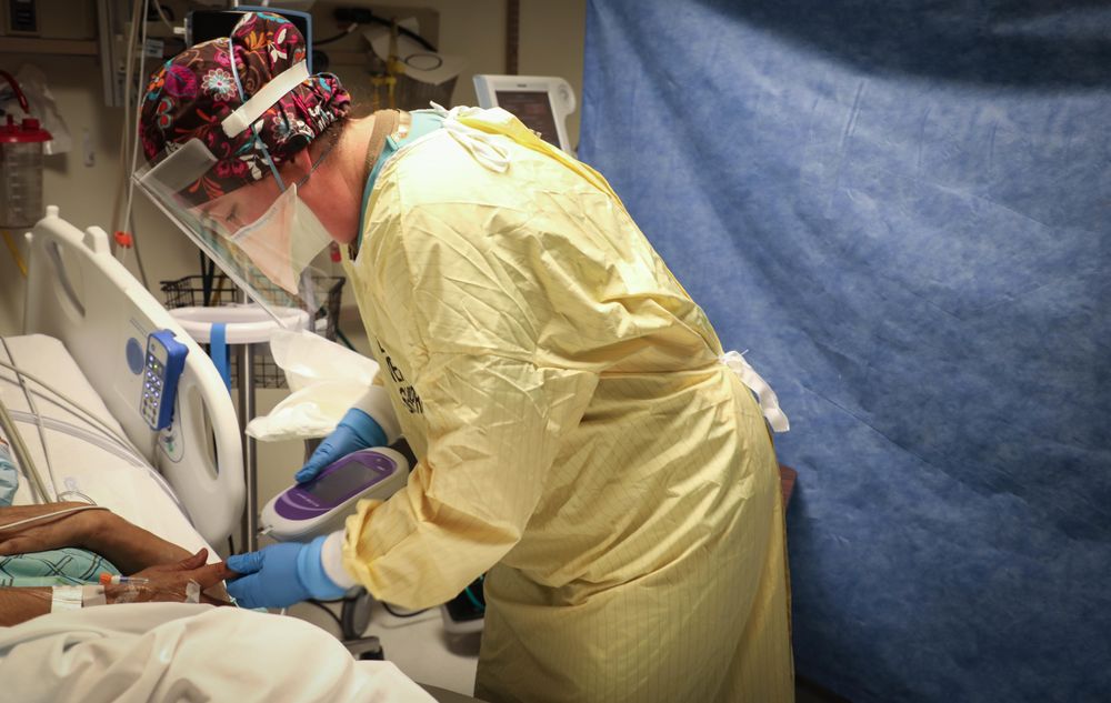 Shiprock, NM - USA, Dec. 31, 2020: Nurse in scrubs and PPE checking blood sugar level of patient