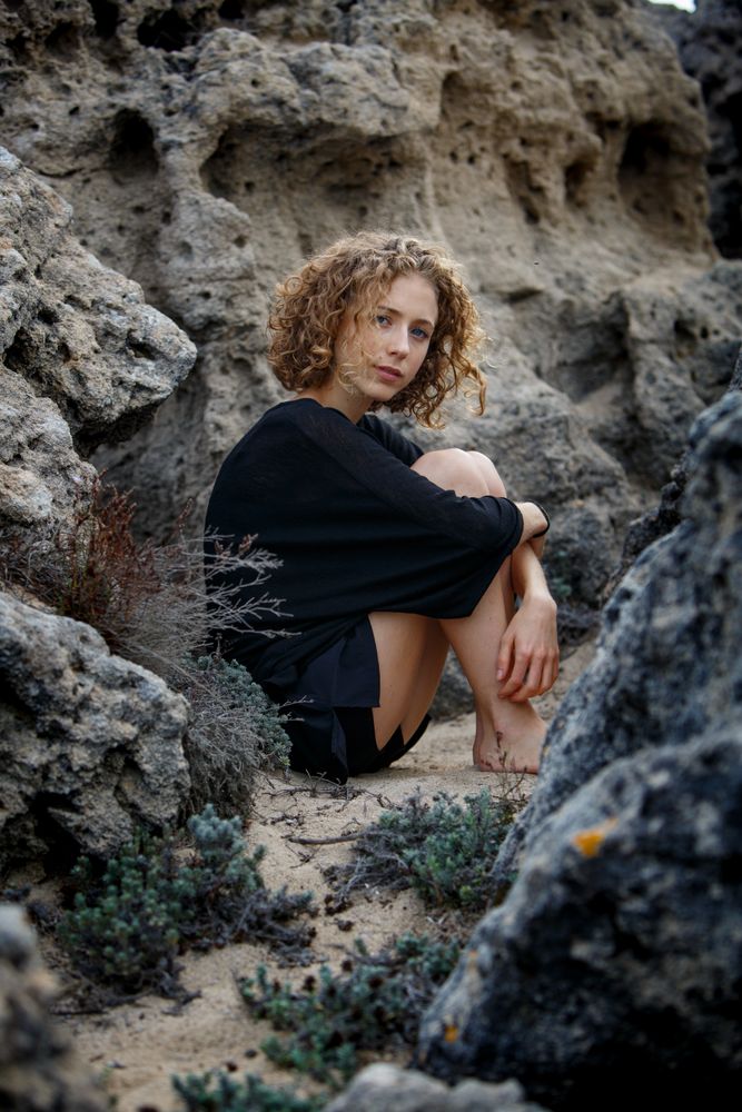 Young woman sitting between stones