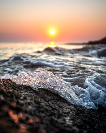 Ocean waves crashing on shore during sunrise in macro photography