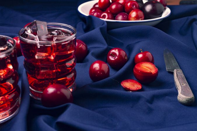 Red beverage near fresh fruits on cloth