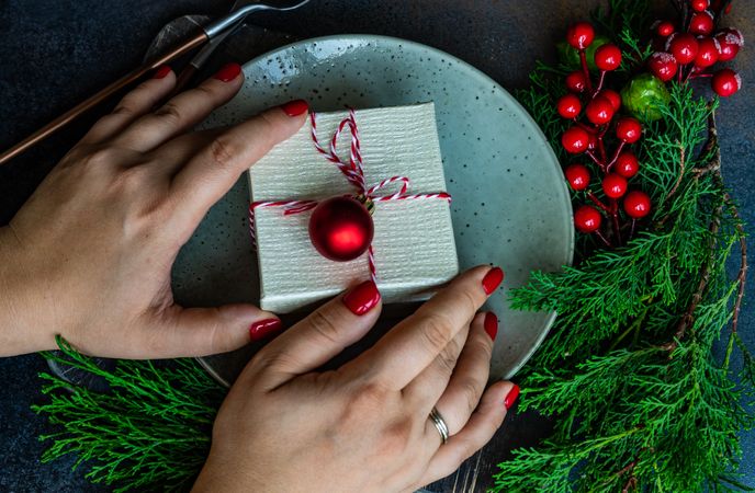 Hands reaching for Christmas present in center of plate