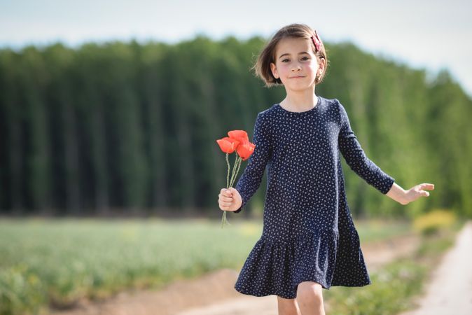 Girl walking in park with red flowers in her hand