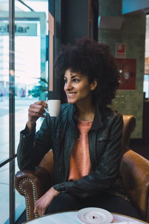 Black woman with afro hair drinking a coffee
