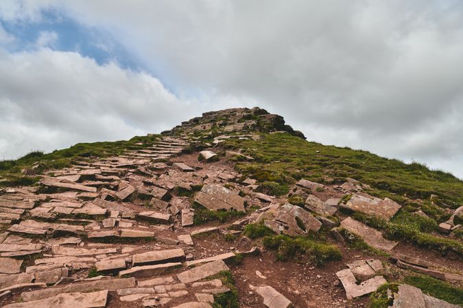 A rock trail leading up a grassy hill