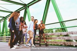 Multiracial people walking together crossing a bridge on a beautiful day bE9pEV
