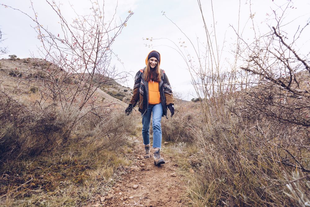 Hiker with backpack walking along pathway in autumn forest