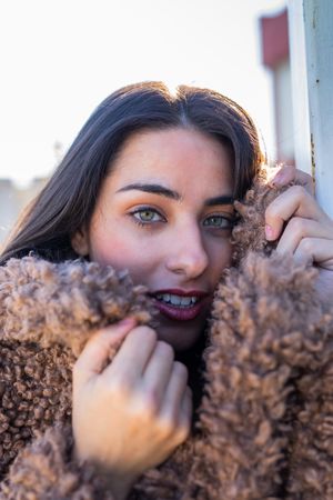 Cheerful woman wrapping in coat on street