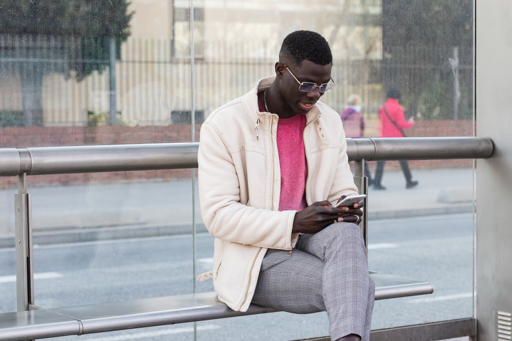Black businessman chatting on smartphone on city street