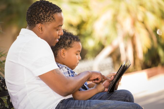 Black Father and Son Using Digital Tablet Outside