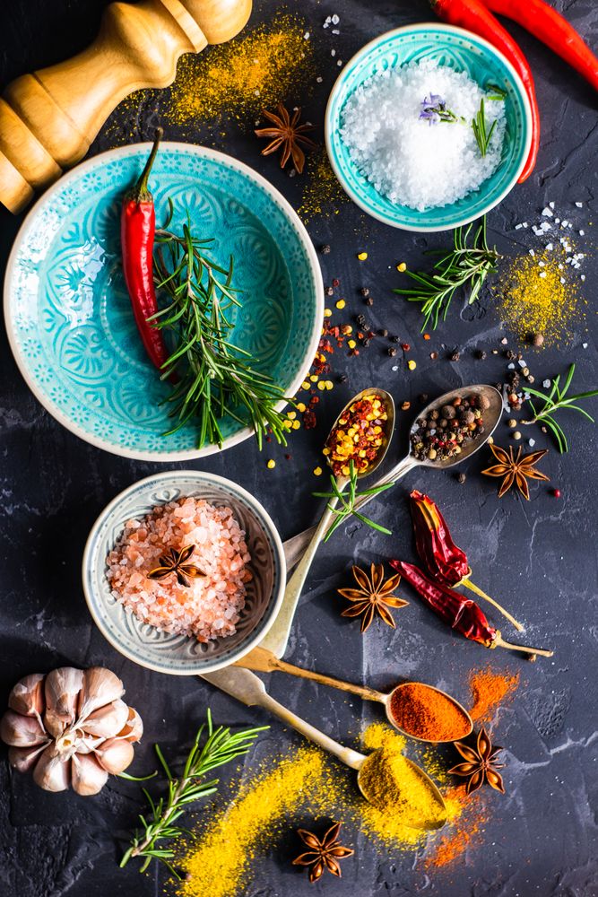 Spices, herbs and salt in teal bowls on counter with copy space