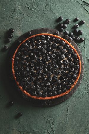 Tray with blueberry pie on green background
