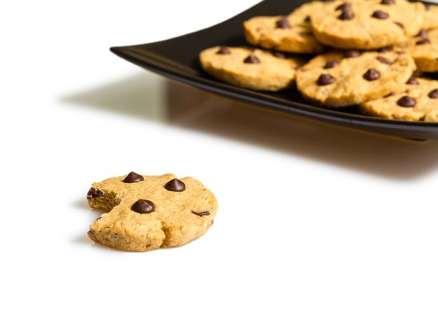 Chocolate chip cookie with a bite and pile of cookies in a plate on the background