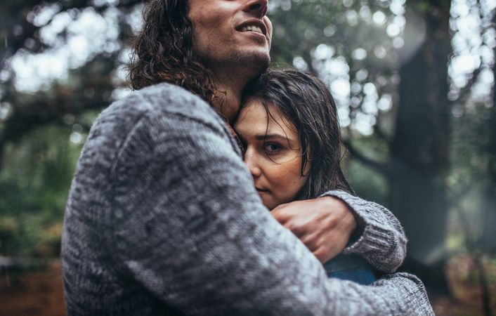 Romantic couple embracing each other in forest in rain