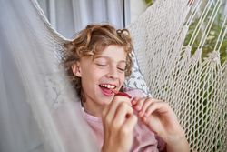 Relaxed adorable child eating popsicle in hammock