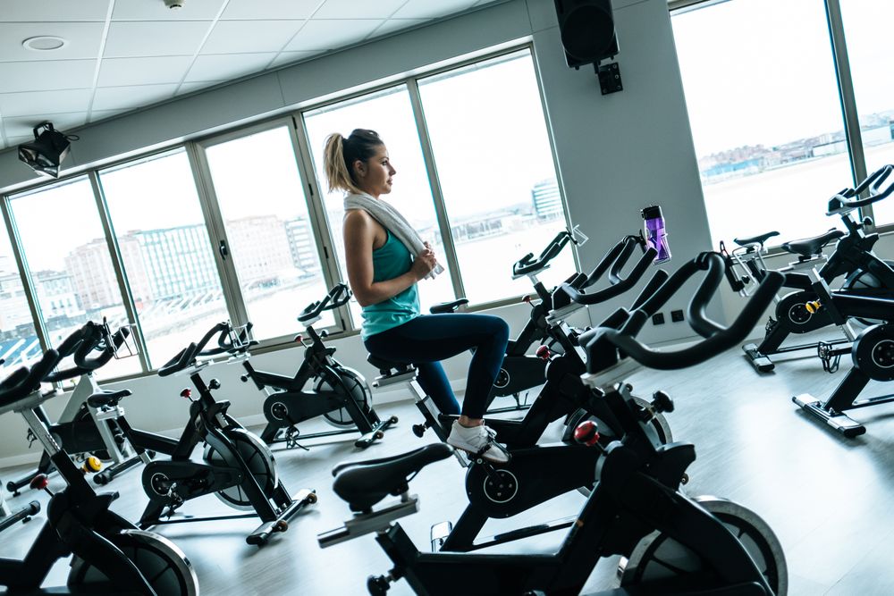 Woman with towel and water on exercise machine