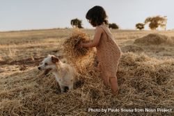 Child lifting piles of hay over her dog 5kdVG4