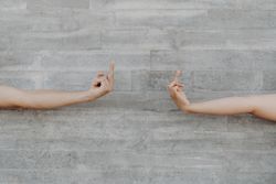 Hands raising finger up background of grey wall