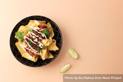 Top view of plate of nachos with salsa, sour cream, limes and cilantro bevR60