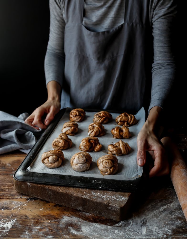 Crop woman with baking pan of cardamom buns